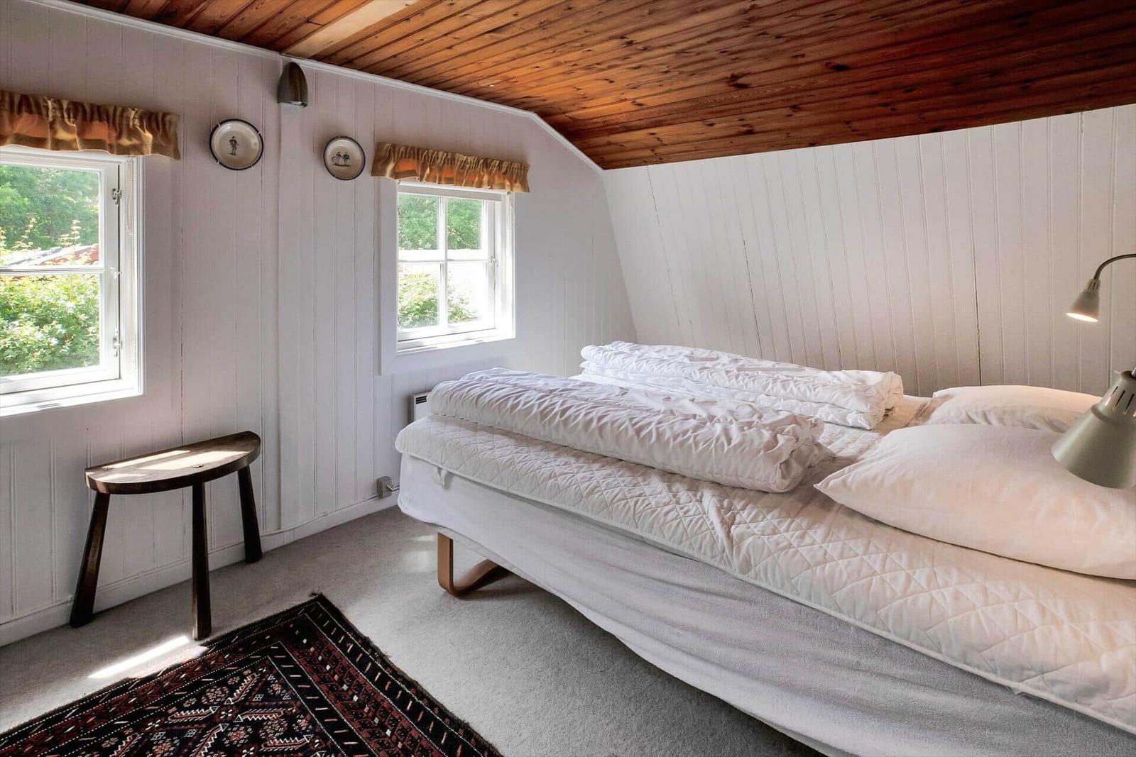 Zimmer mit zwei Betten, Schreibtisch, Fenstern und Holzdecke.