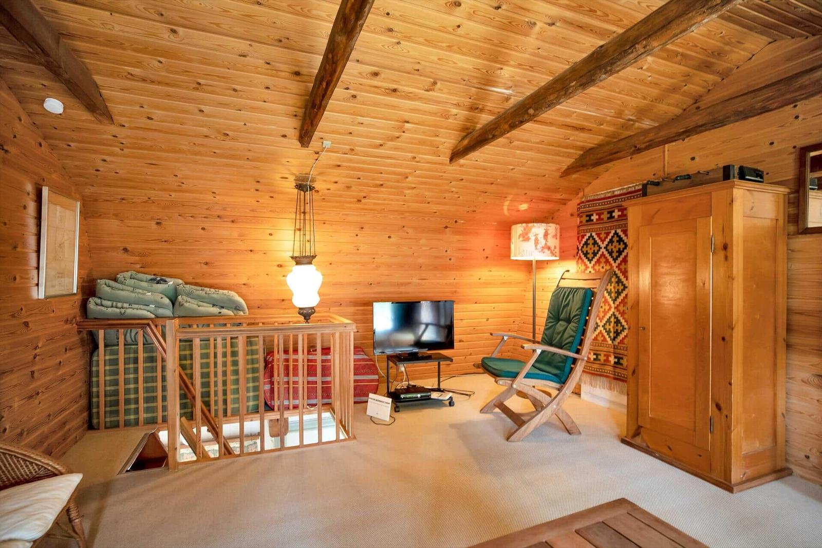 Schlafzimmer mit Doppelbett, Holzdecke und Fenster. An der Wand hängt ein Bild.