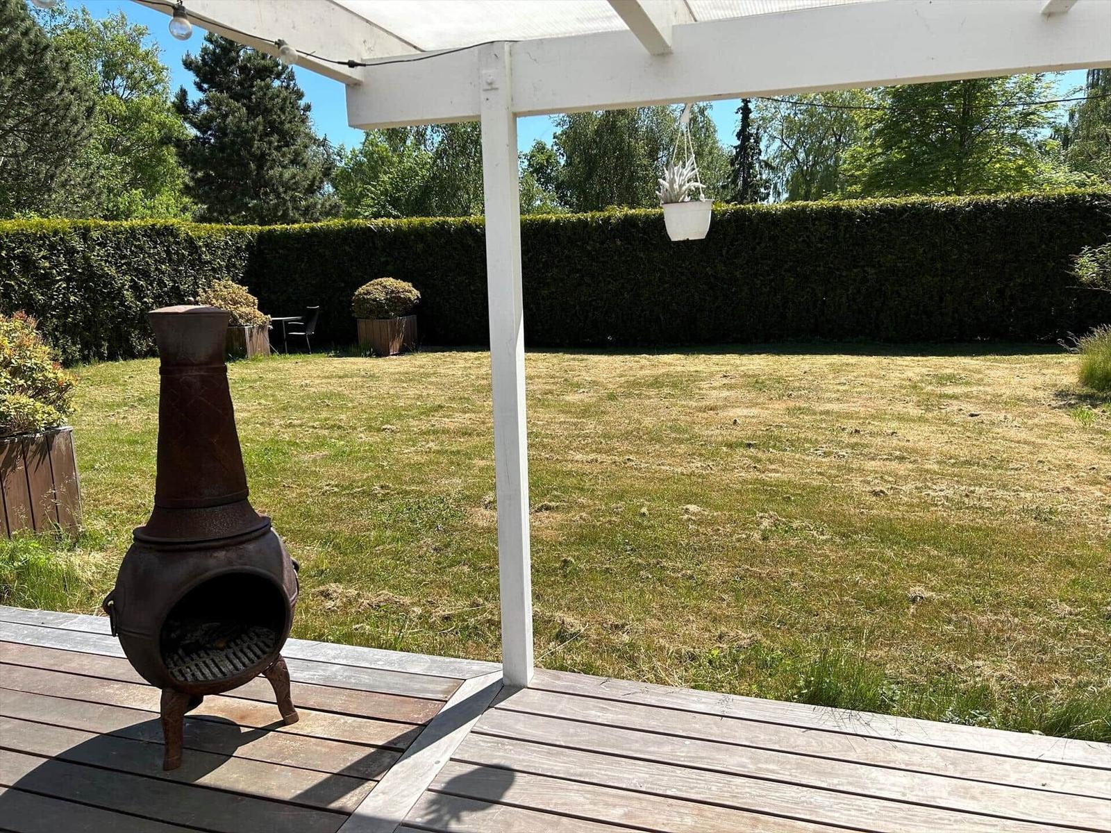 Ein Esszimmer mit weißem Tisch, Stühlen und Kamin. Durch große Fenster ist eine Terrasse sichtbar.