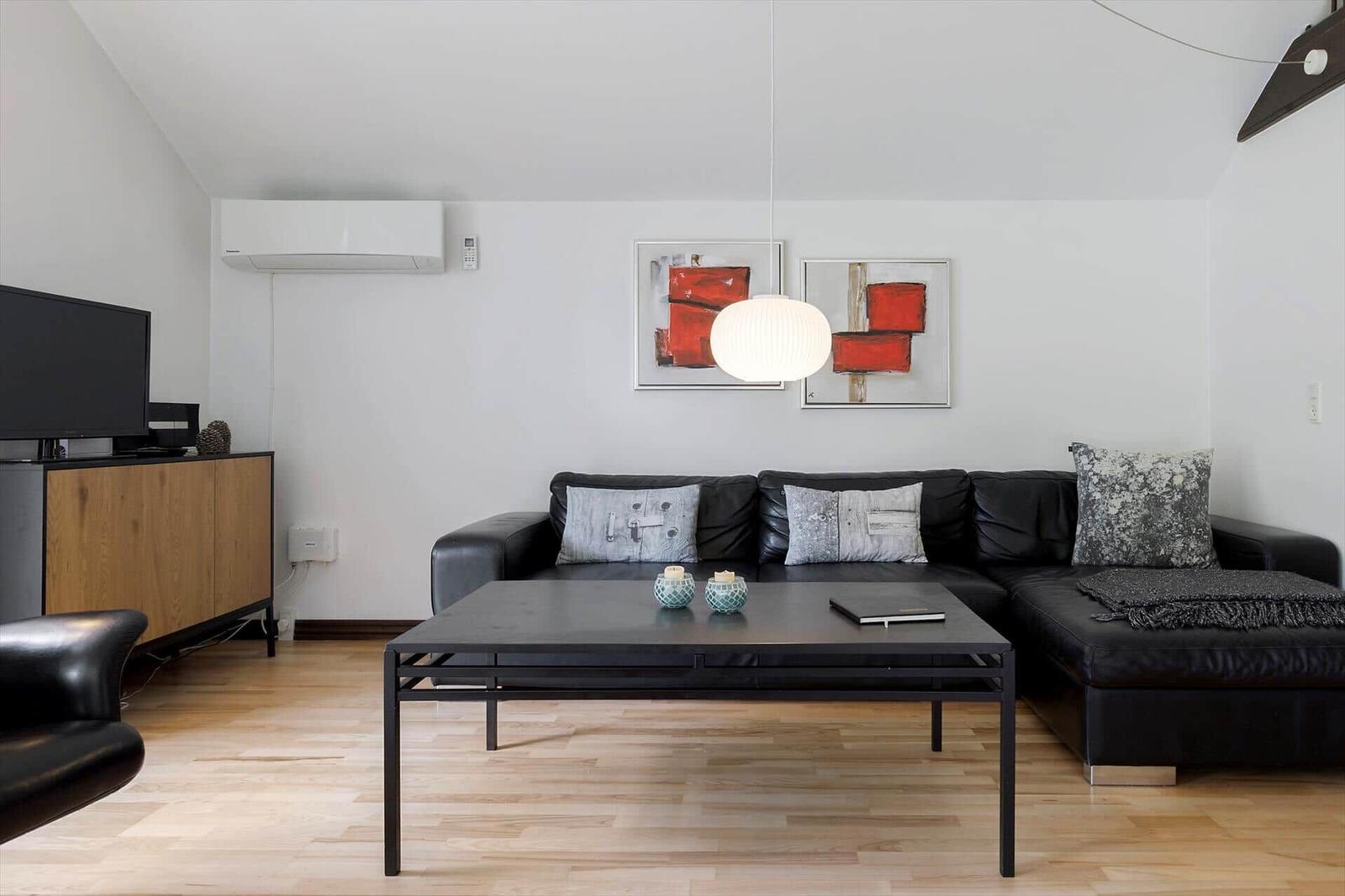 Ein Schlafzimmer mit weißer Bettwäsche, zwei Wandlampen und einem Fenster mit Pflanzen.