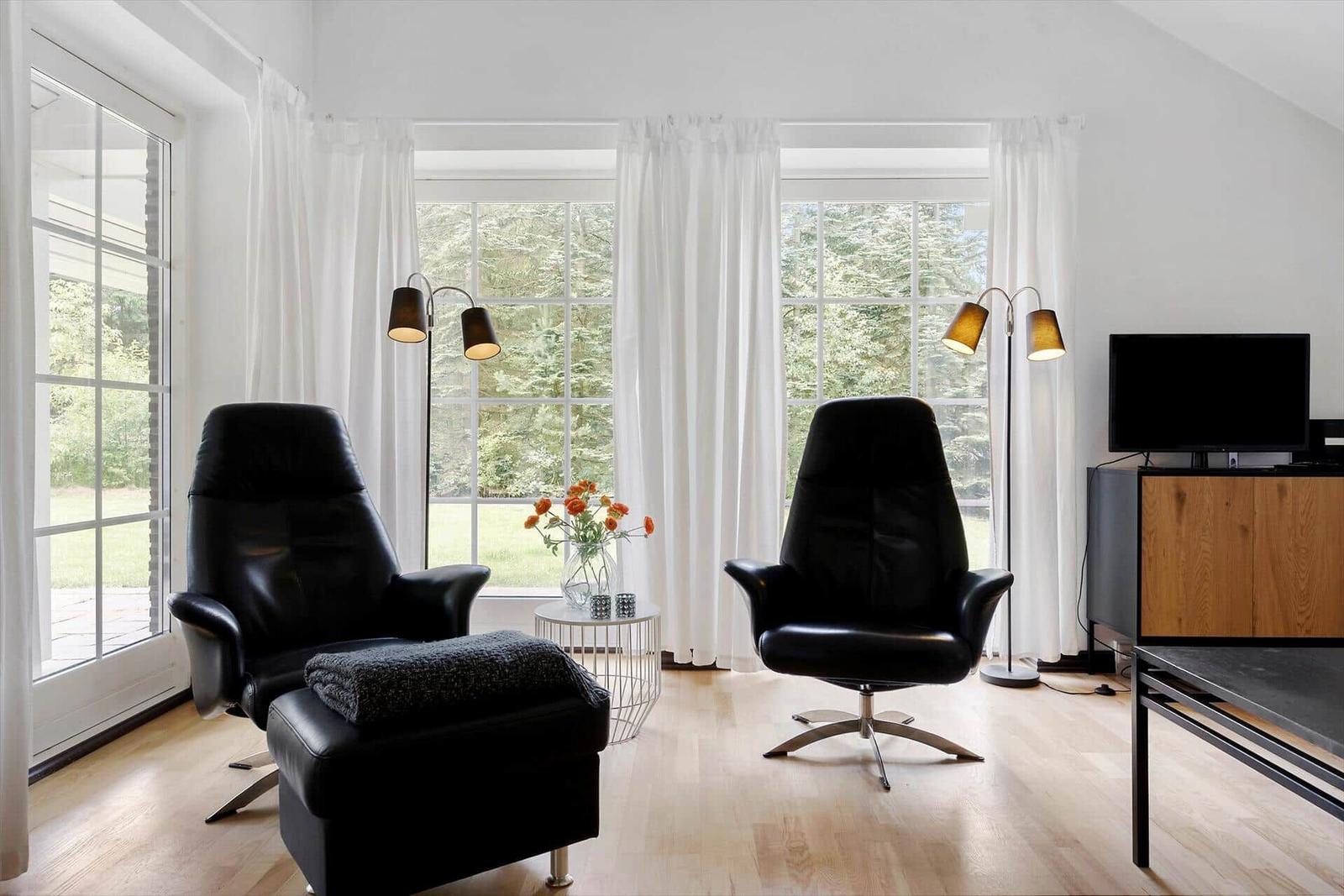 Schlafzimmer mit Bett, Fenster, Wand-TV und Wandlampe.