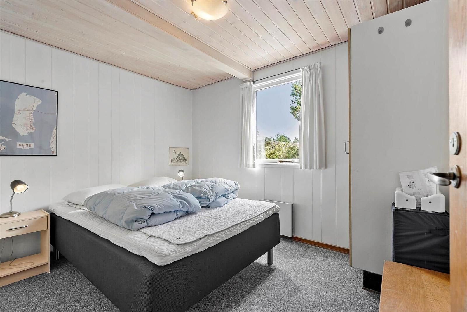 Wohn- und Essbereich mit Küche, TV, Sofa und Stühlen. Holzdecke und Fenster zur Außenterrasse.