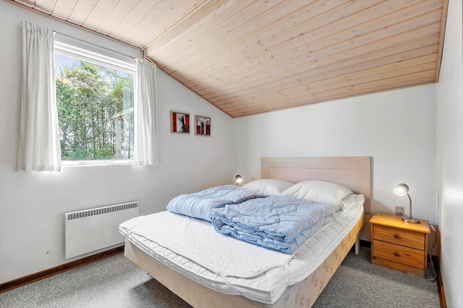 Schlafzimmer mit Bett, Fenster und Kleiderschrank.