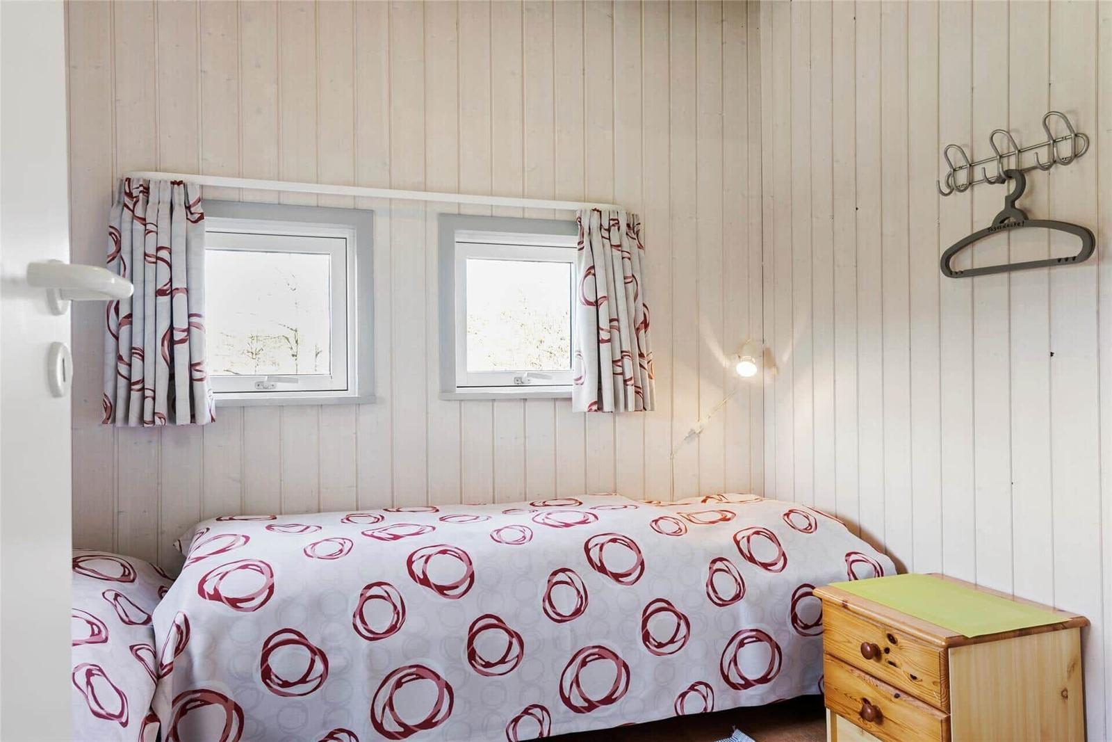 Roter Holzhaus mit weißem Balkon und gelbem Tisch mit Tassen.