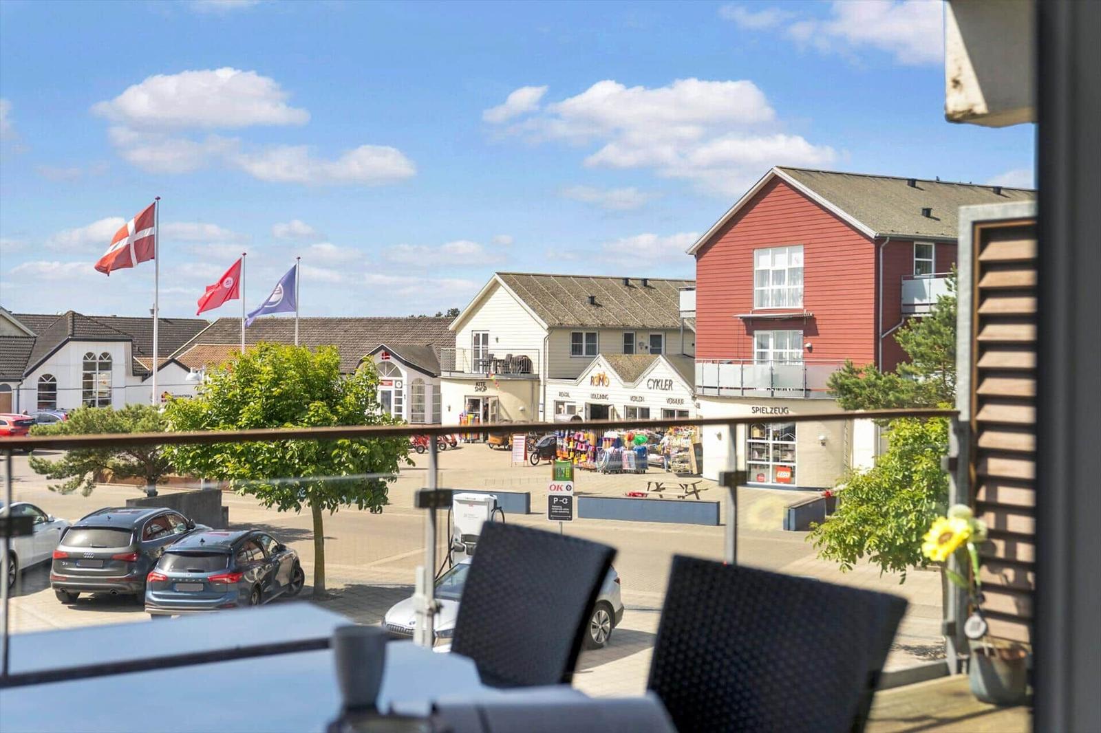 Terrasse mit Tisch, Stühlen und Tasse. Hintergrund: Holzverkleidung und Glastür.