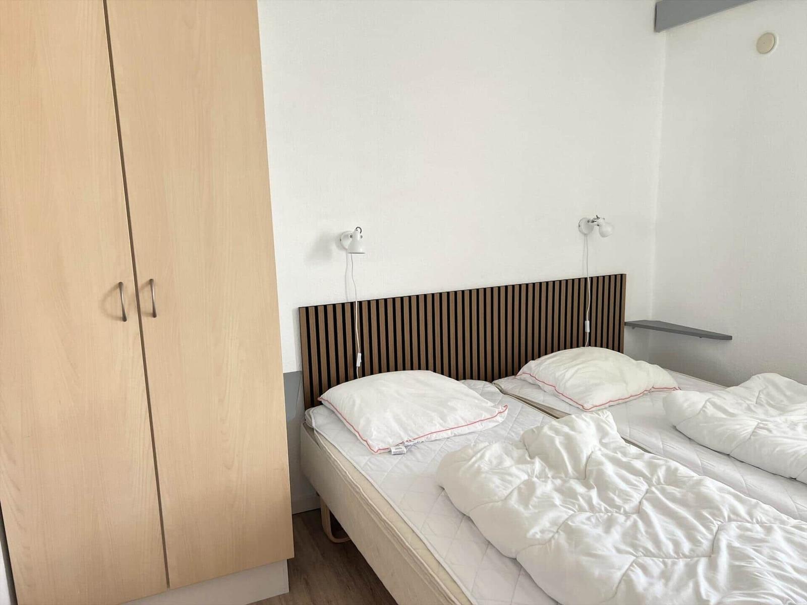 Wohnzimmer mit Sofa, Esstisch und Terrassentür. Holzfußboden und Holzwand.