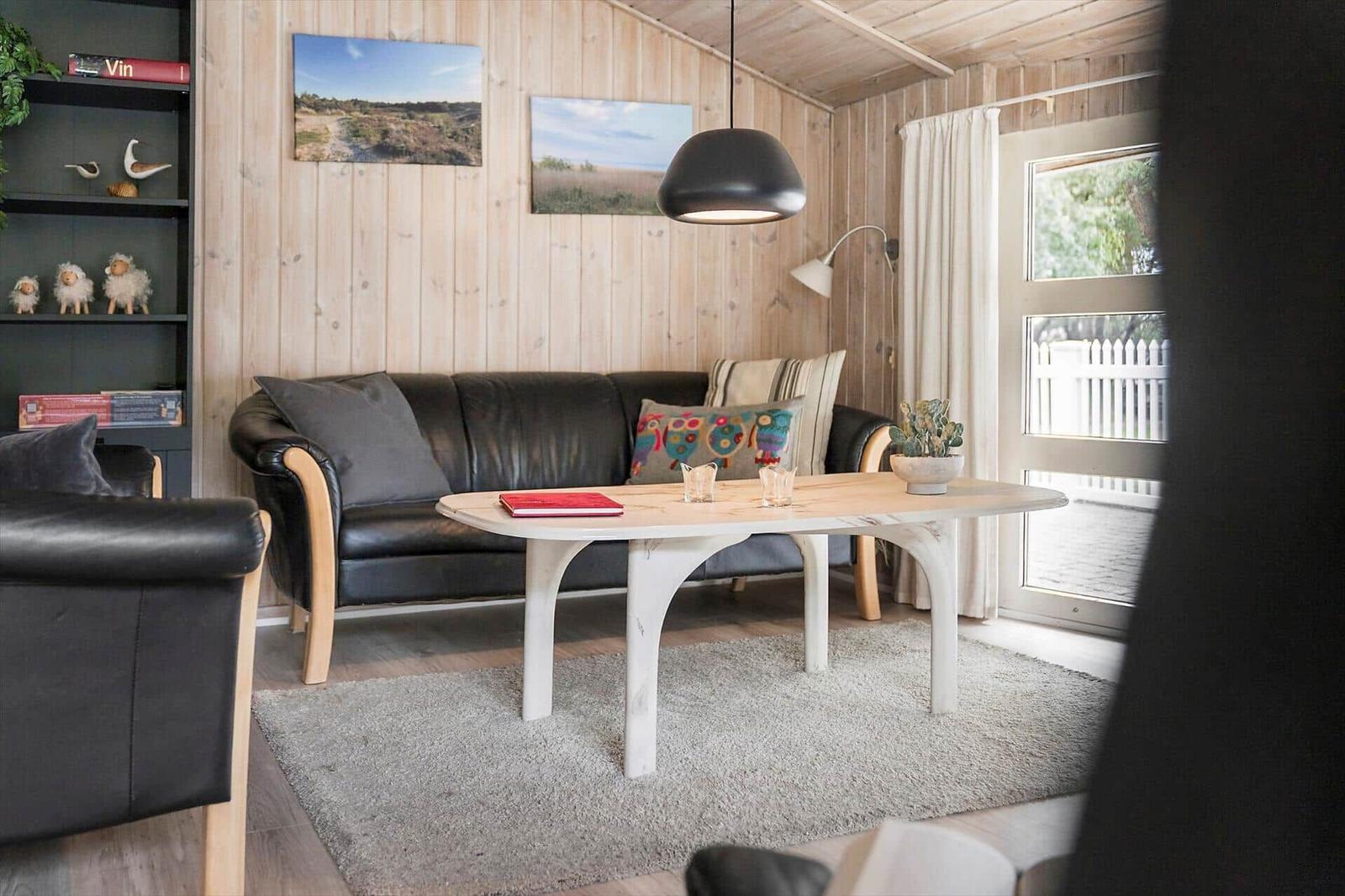 Haus mit Spielplatz, weißer Zaun und Bäumen im Hintergrund.