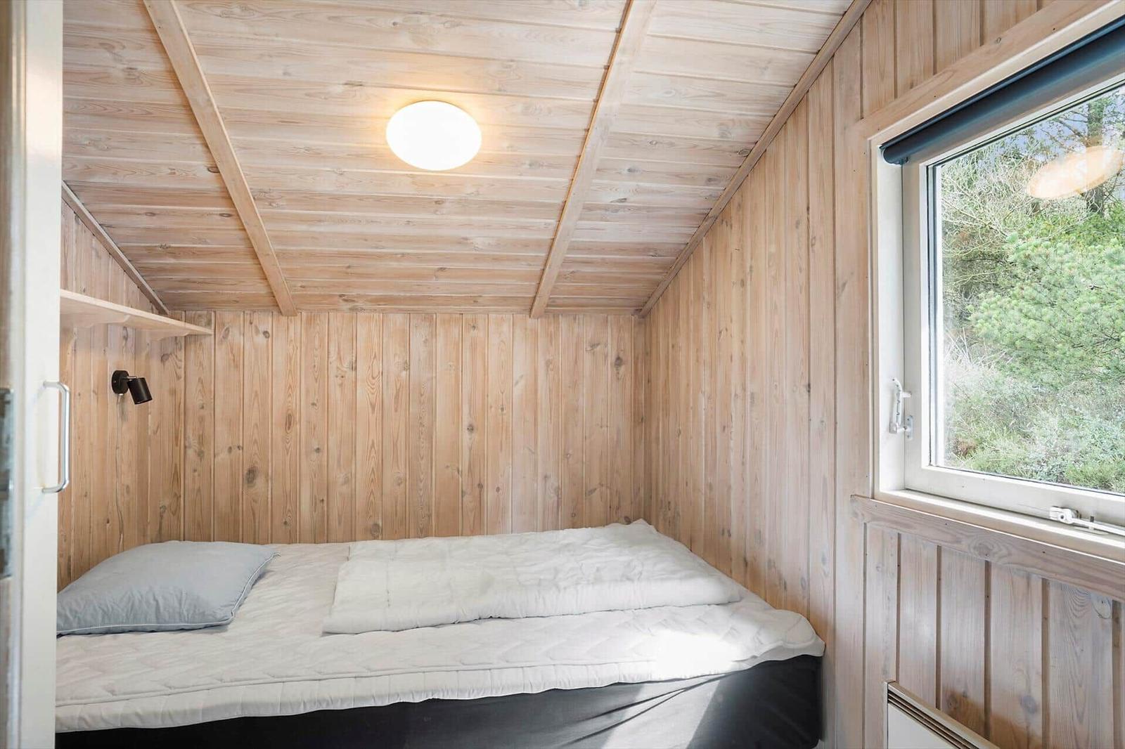 Wohnzimmer mit Holzwänden, Kamin und TV. Es gibt schwarze Ledersofas und einen ovalen Tisch.