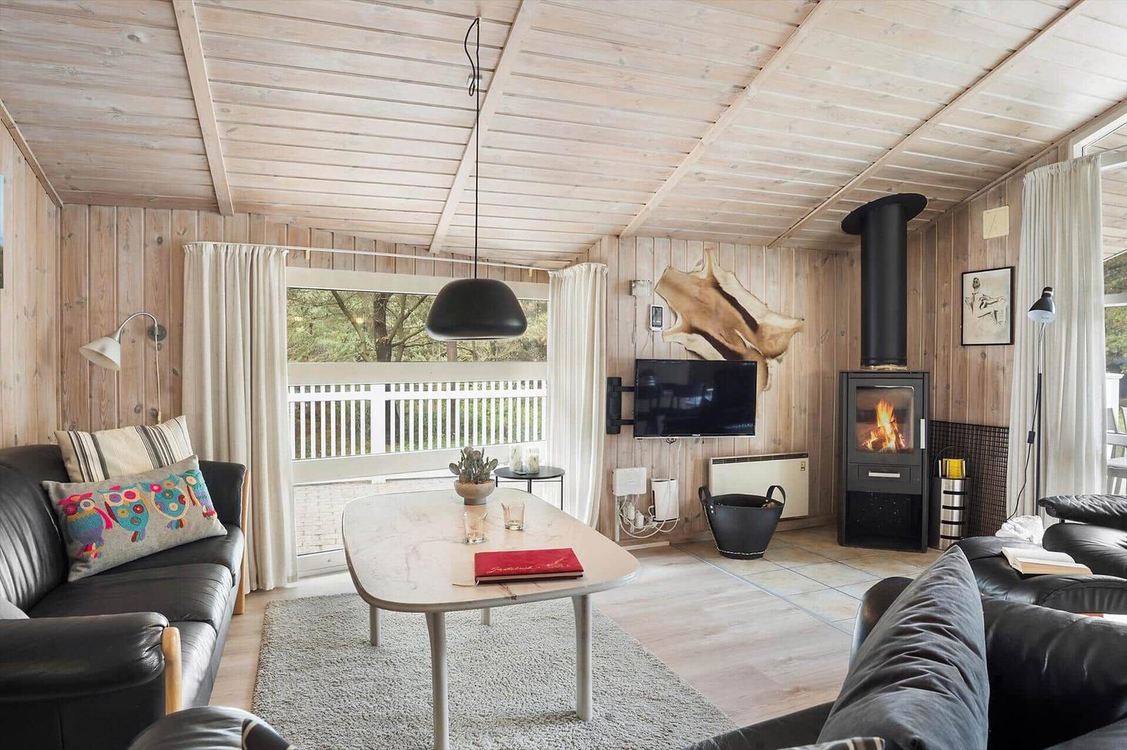 Ein Wohnzimmer mit Holzwänden, einem schwarzen Sofa und einem weißen Tisch.
