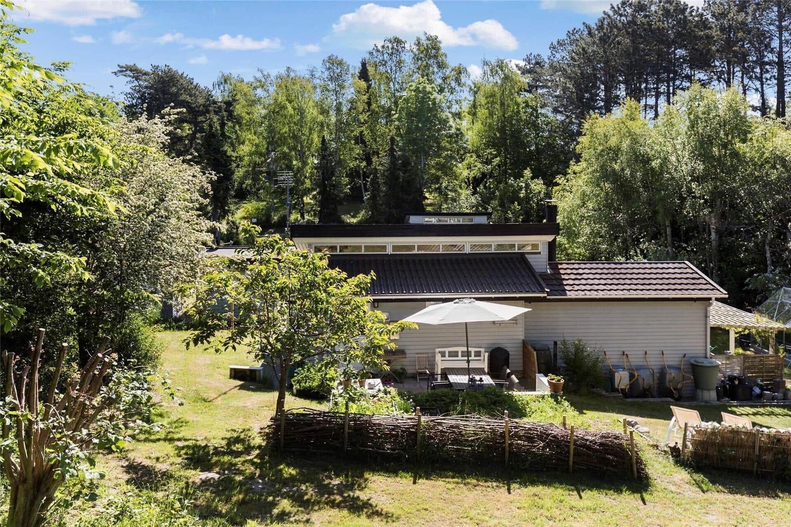 Terrasse mit Holzdielen, Sitzbank aus Paletten, Tisch und Stühle, zwei Sonnenschirme und Blick in den Garten.