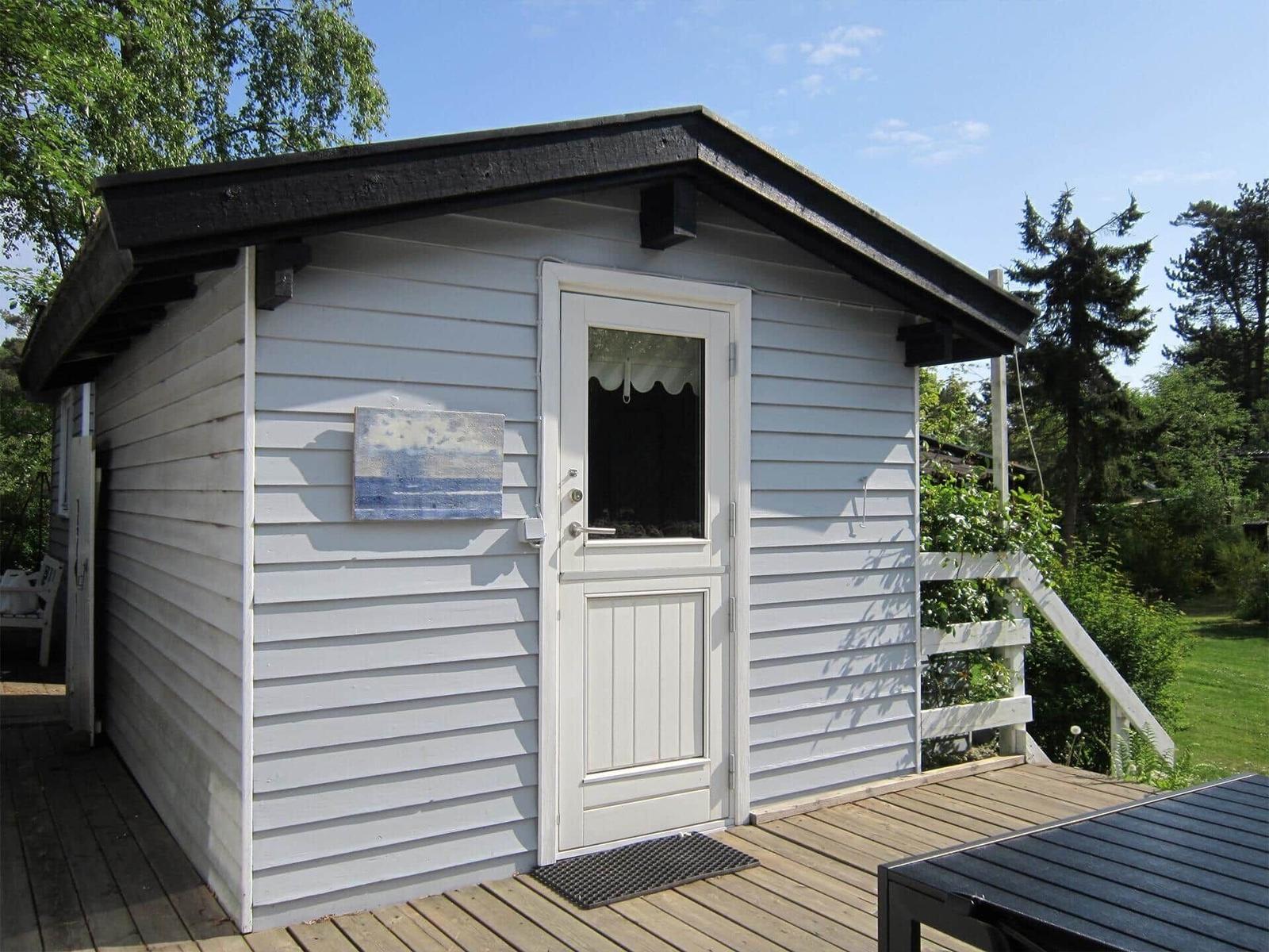 Haus mit großem Glasbereich und Garten mit Blumenbeeten und Pergola.