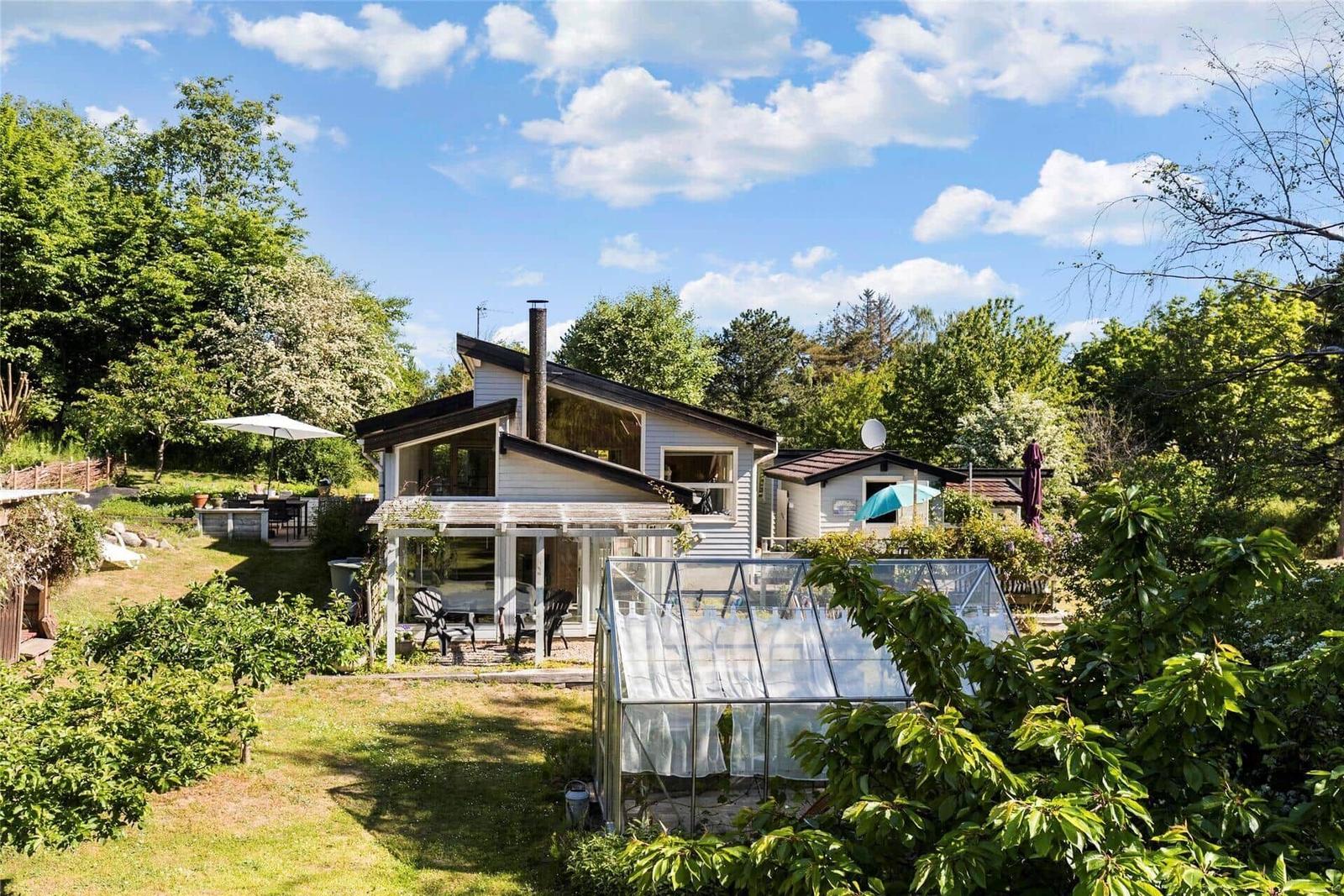 Terrasse mit Tisch, Stühlen, Grill und weißem Bänkchen vor einem Haus.