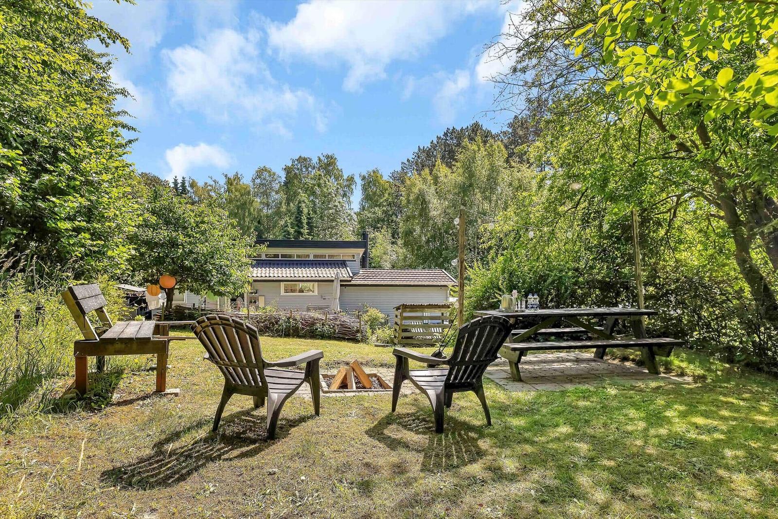 Küche mit Essbereich, Holzboden und weißen Schränken. Tisch mit Tischdecke und Blumen.