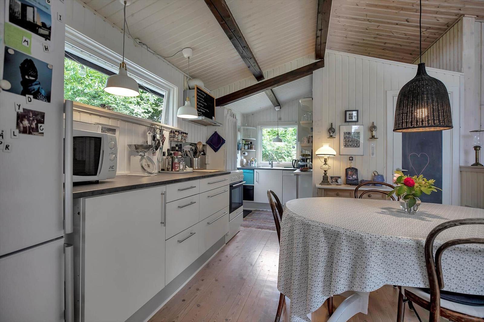 Wohnhaus mit weißen Holzwänden, Tür und Terrasse. An der Wand hängt ein Bild.