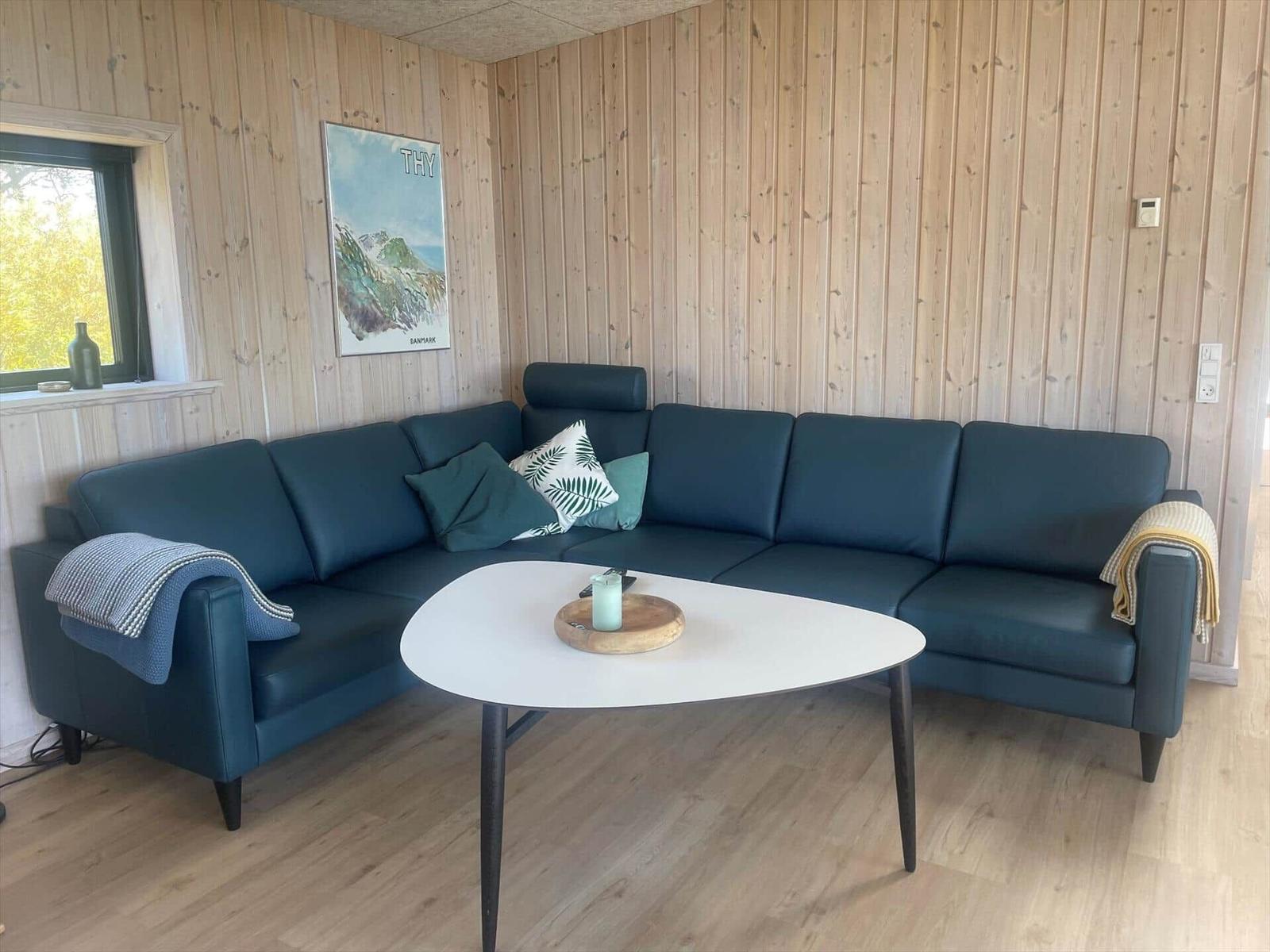 Ein Wohnzimmer mit einem blauen Sofa, einem weißen Tisch und Holzwänden.