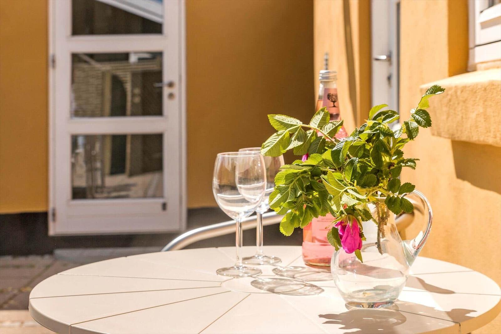 Außenbereich mit weißem Tisch und Bänken vor gelbem Haus