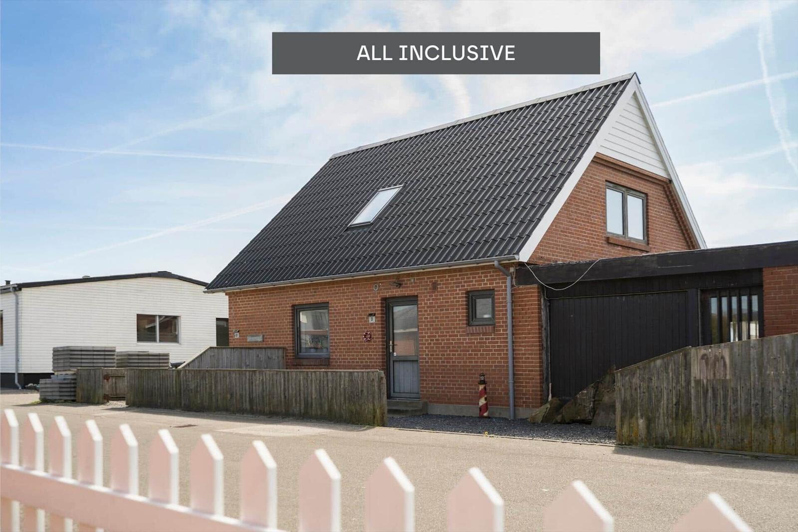 Ein Haus mit rotem Backstein, schwarzem Dach und Holzzaun. Alle Inklusivangebote.