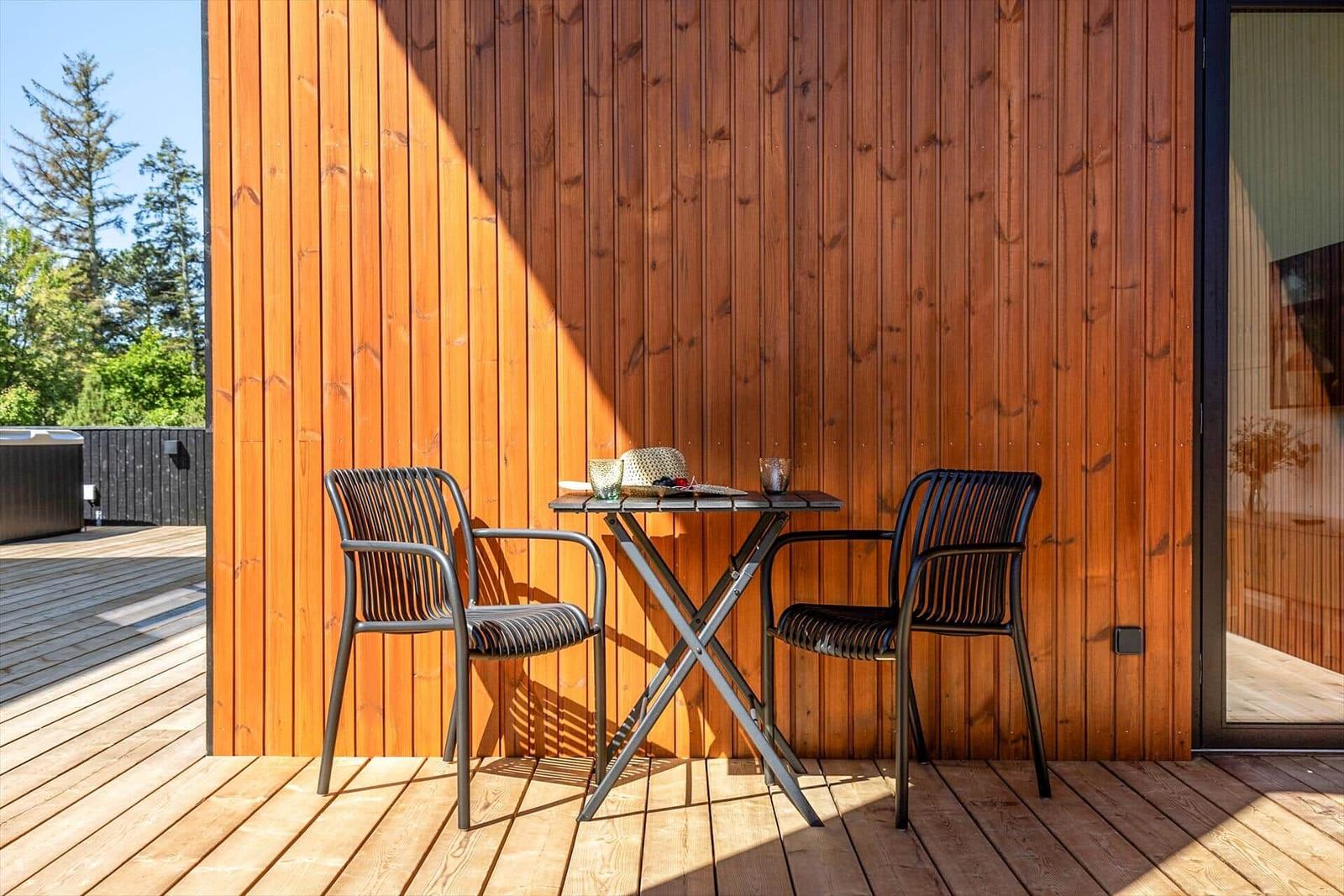 Terrasse mit Tisch und zwei Stühlen vor Holzwand