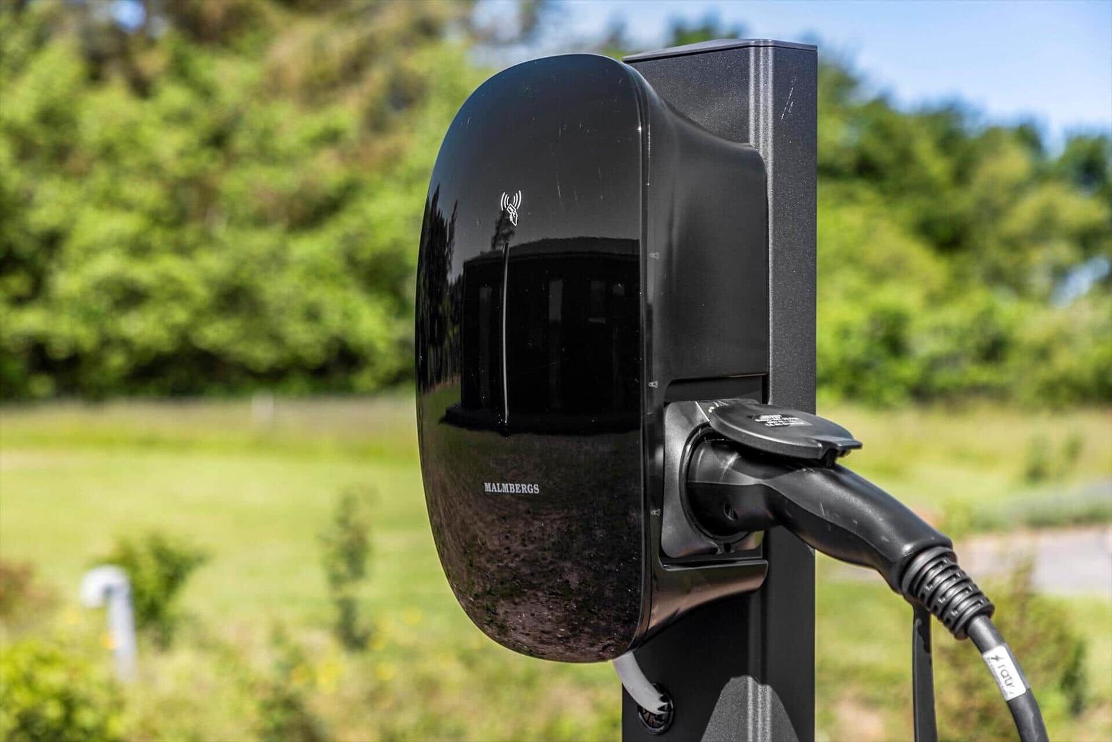 Elektrischer Ladekabel für E-Auto an Außensäule mit grünem Hintergrund