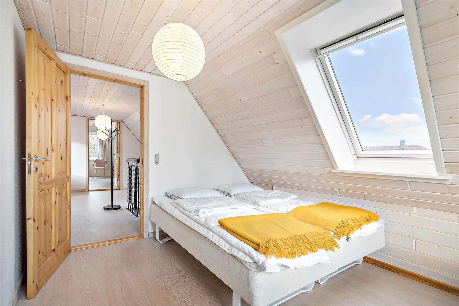 Schlafzimmer mit Doppelbett, Nachttisch und Holztür