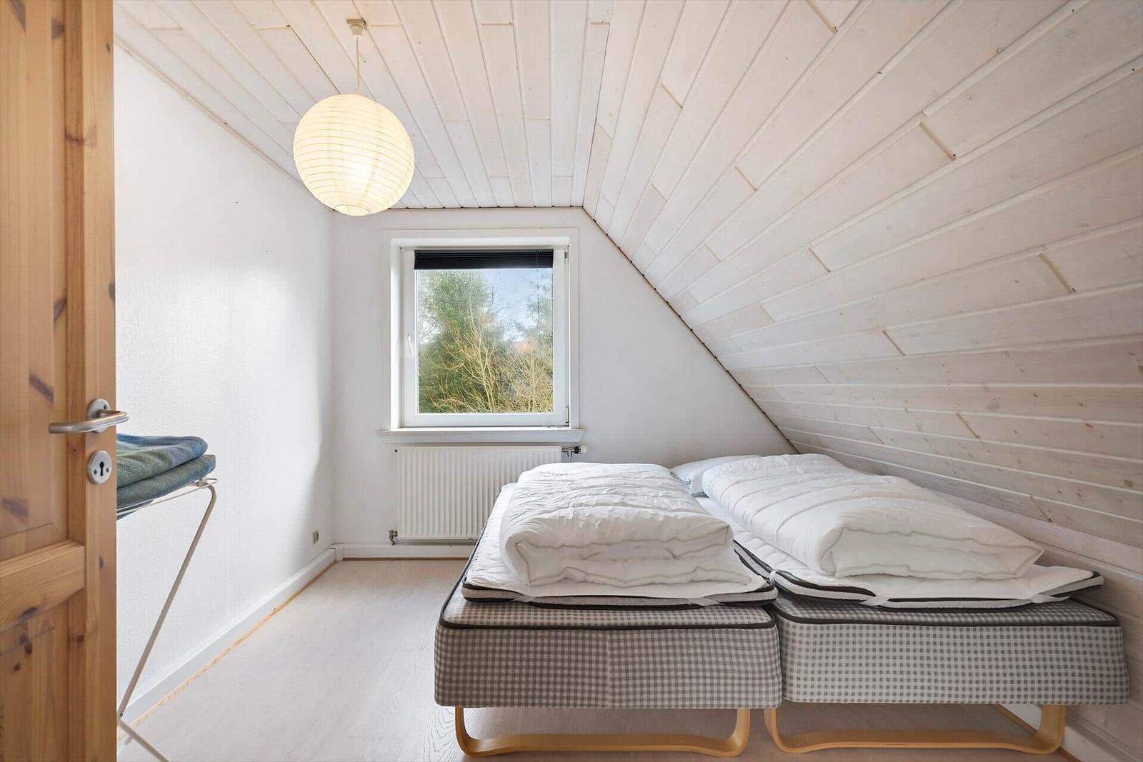 Ein grauer Sofa im Dachgeschoss mit Fenster und Holzwand.