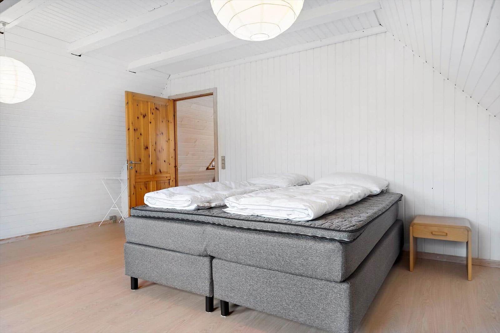 Wohnzimmer mit grauem Sofa, Holzwand und Dachfenster.