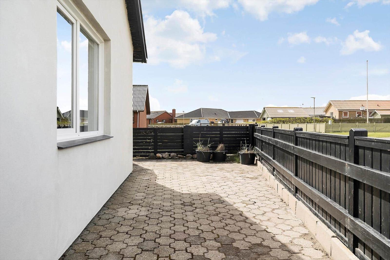 Moderne Villa mit Garten und Terrasse. Schwarz-weiße Fassade und Holzdetails.
