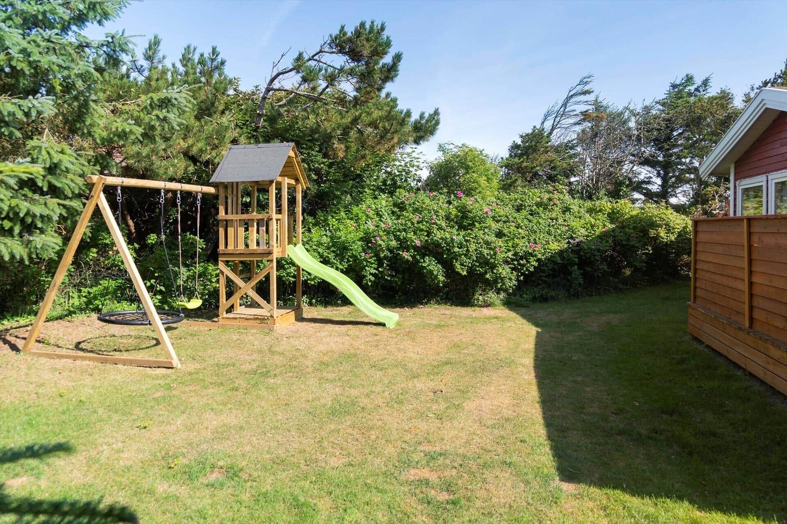 Hinterhof mit Holzspielplatz, Schaukel und Rutsche auf Rasenfläche.