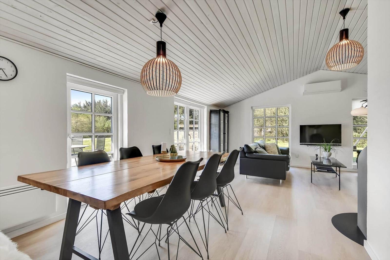 Essbereich mit Holztisch und schwarzen Stühlen. Küche mit weißen Schränken im Hintergrund.