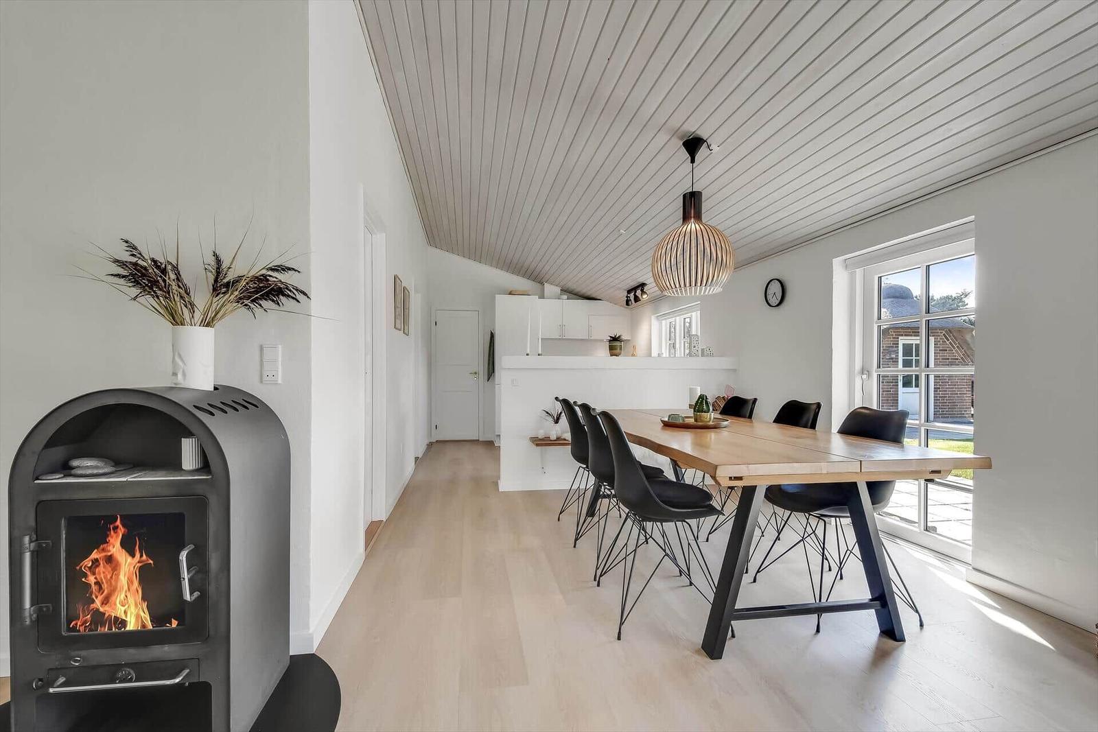 Esszimmer mit Holztisch, schwarzen Stühlen und Deckenventilator.