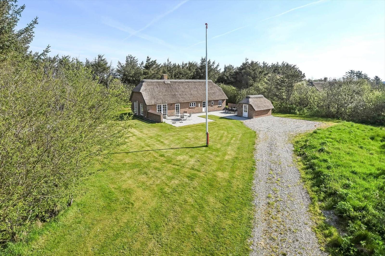 Haus mit Strohdach, Garten und Terrasse in grüner Umgebung