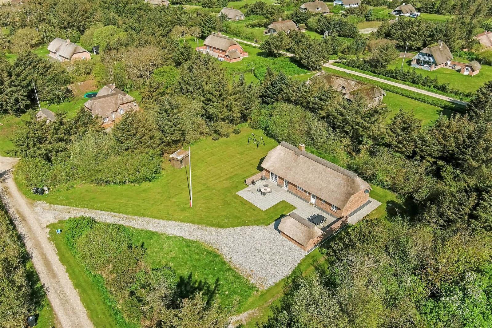 Haus mit Strohdach, Terrasse und Garten. Umgeben von Wald und Feldern.