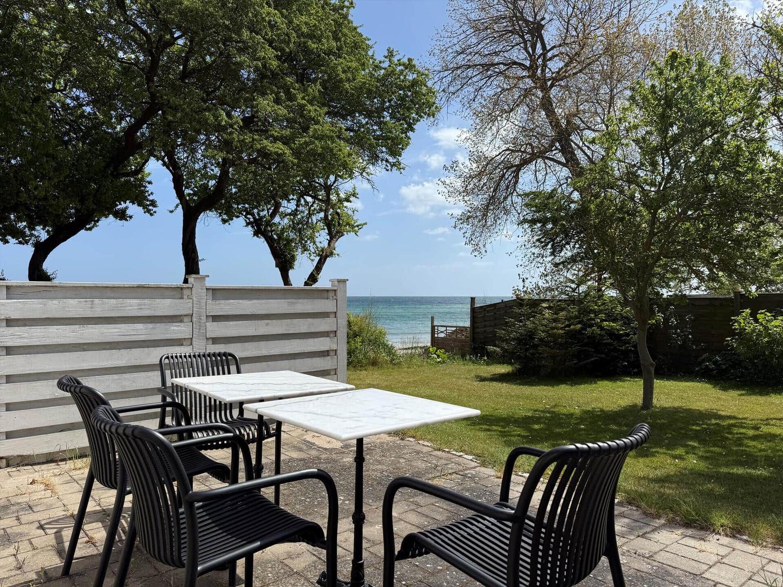 Haus mit rotem Dach und Flagge, umgeben von Bäumen und Blick auf das Meer.