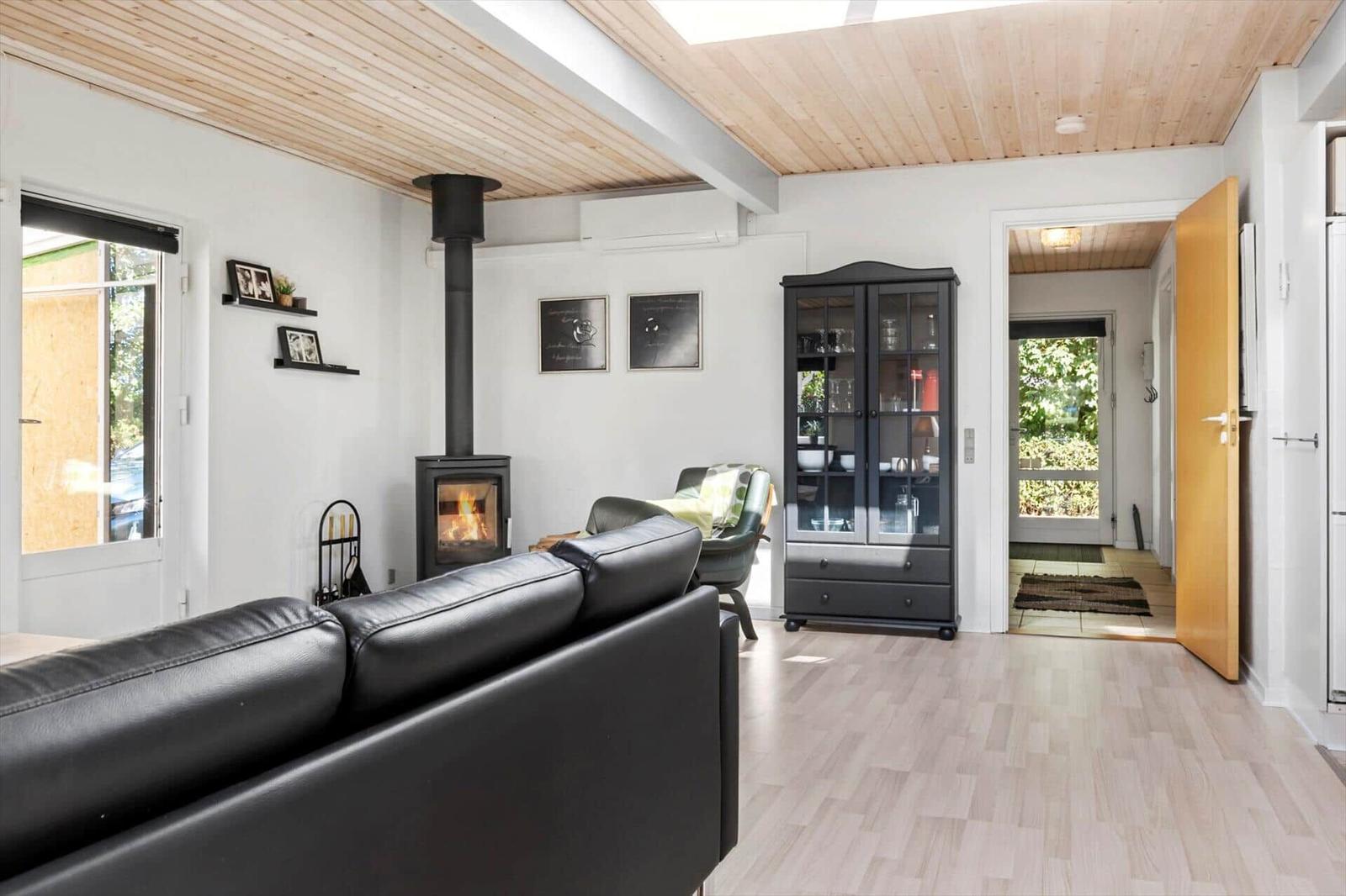 Wooden table and fire pit on paved area with flowering hedge and grass lawn.