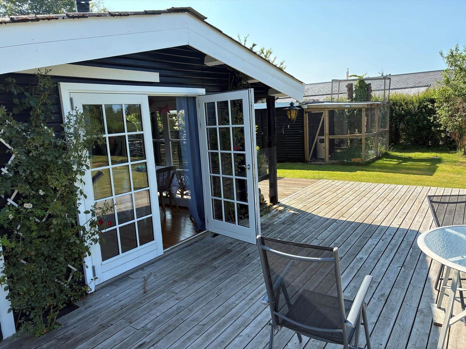 Wohn- und Essbereich mit Kamin, Tisch, Sofa und Blick auf den Garten.