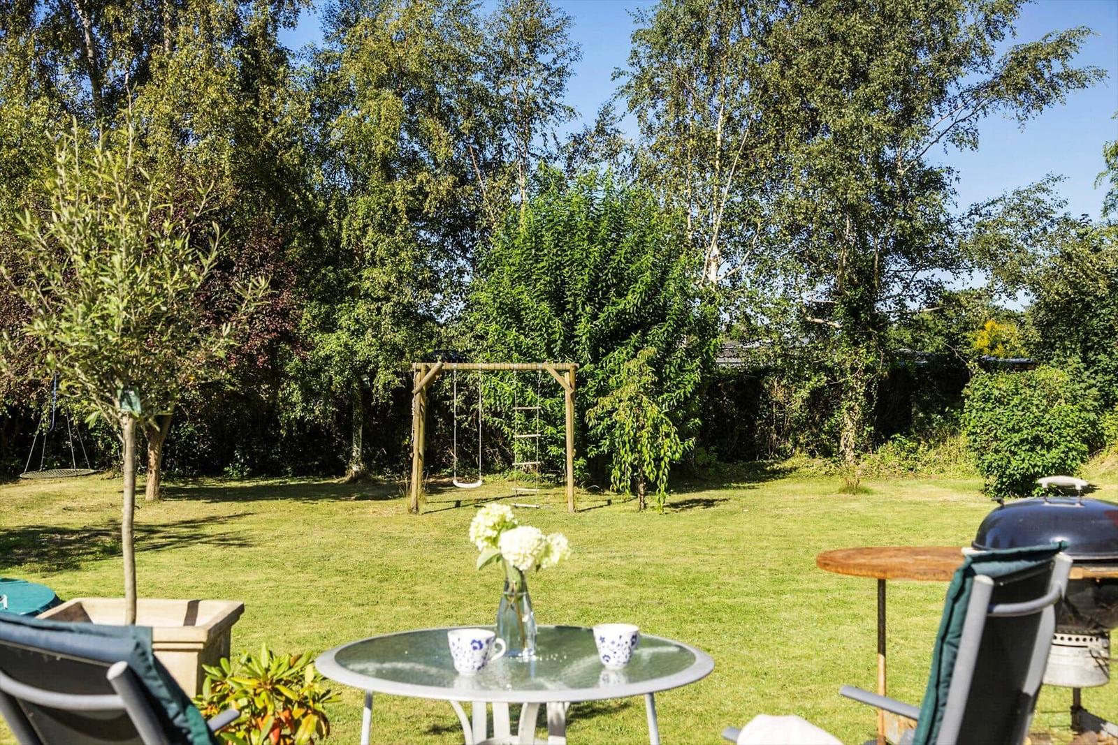 Gartenbereich mit Esstisch, Sitzbank und Fenster. Holzboden und Dachkonstruktion.