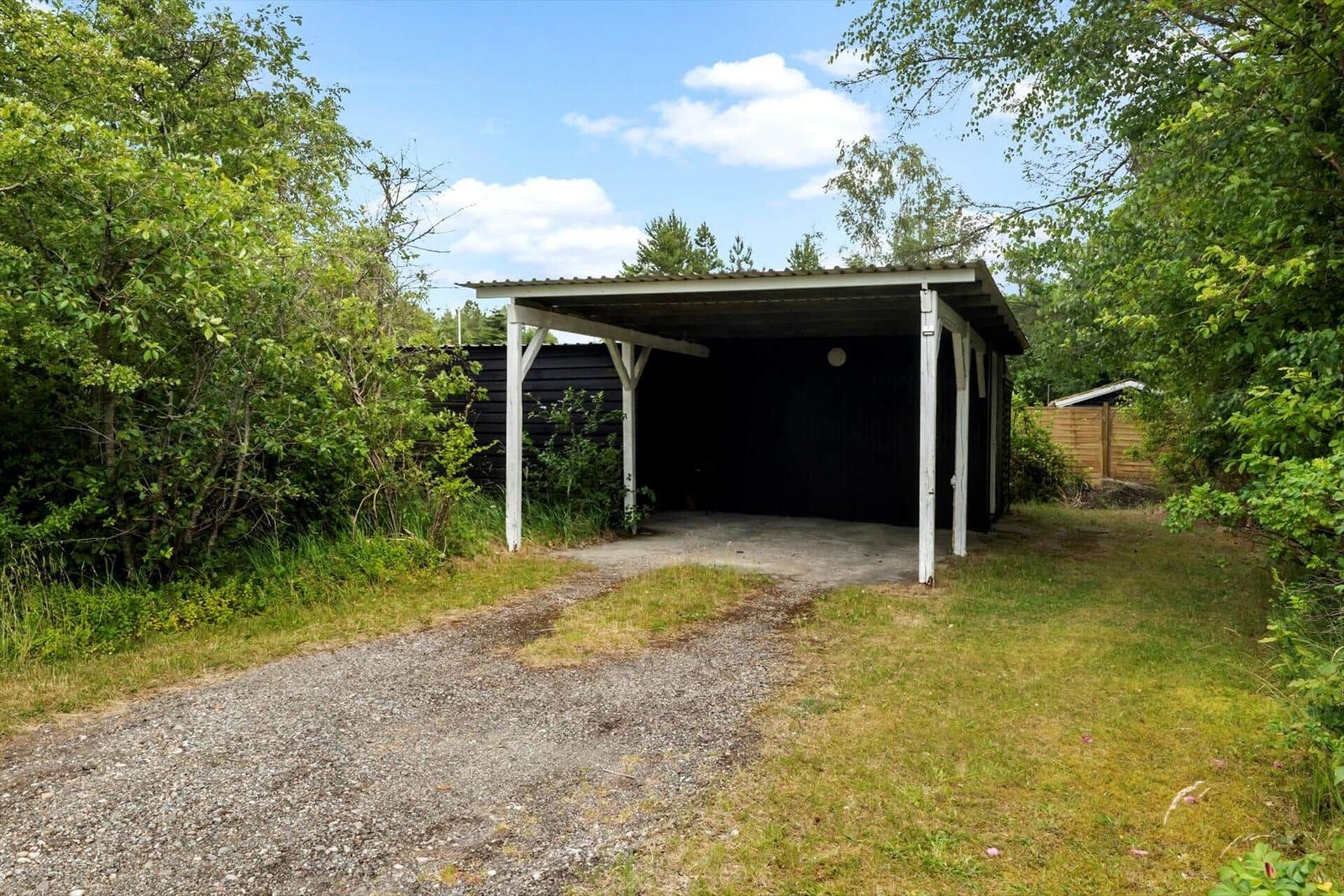 Hinterhof mit Sitzgruppe, Grill und Pflanzen vor schwarzem Haus.