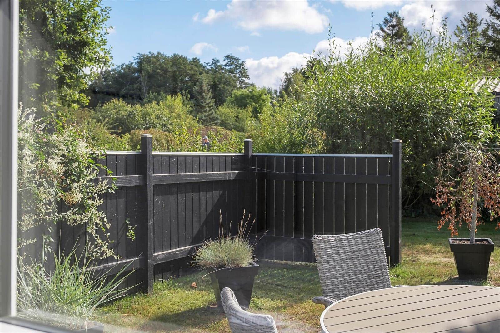 An outdoor terrace with chair, table, and wine. Hanging basket and plants are visible.