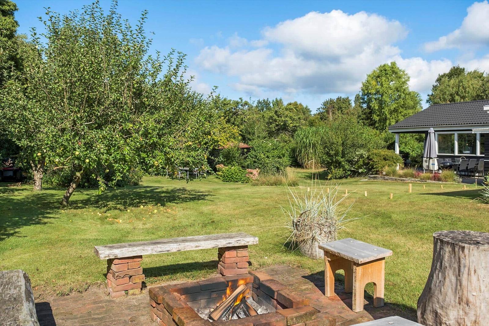 Garden with table and chairs, flower beds, and view of wooden house.