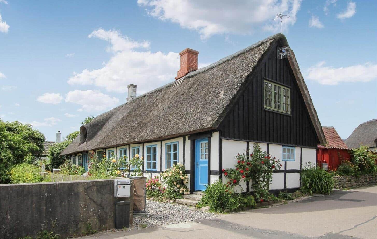 Traditionelles Haus mit Strohdach und blauer Tür.