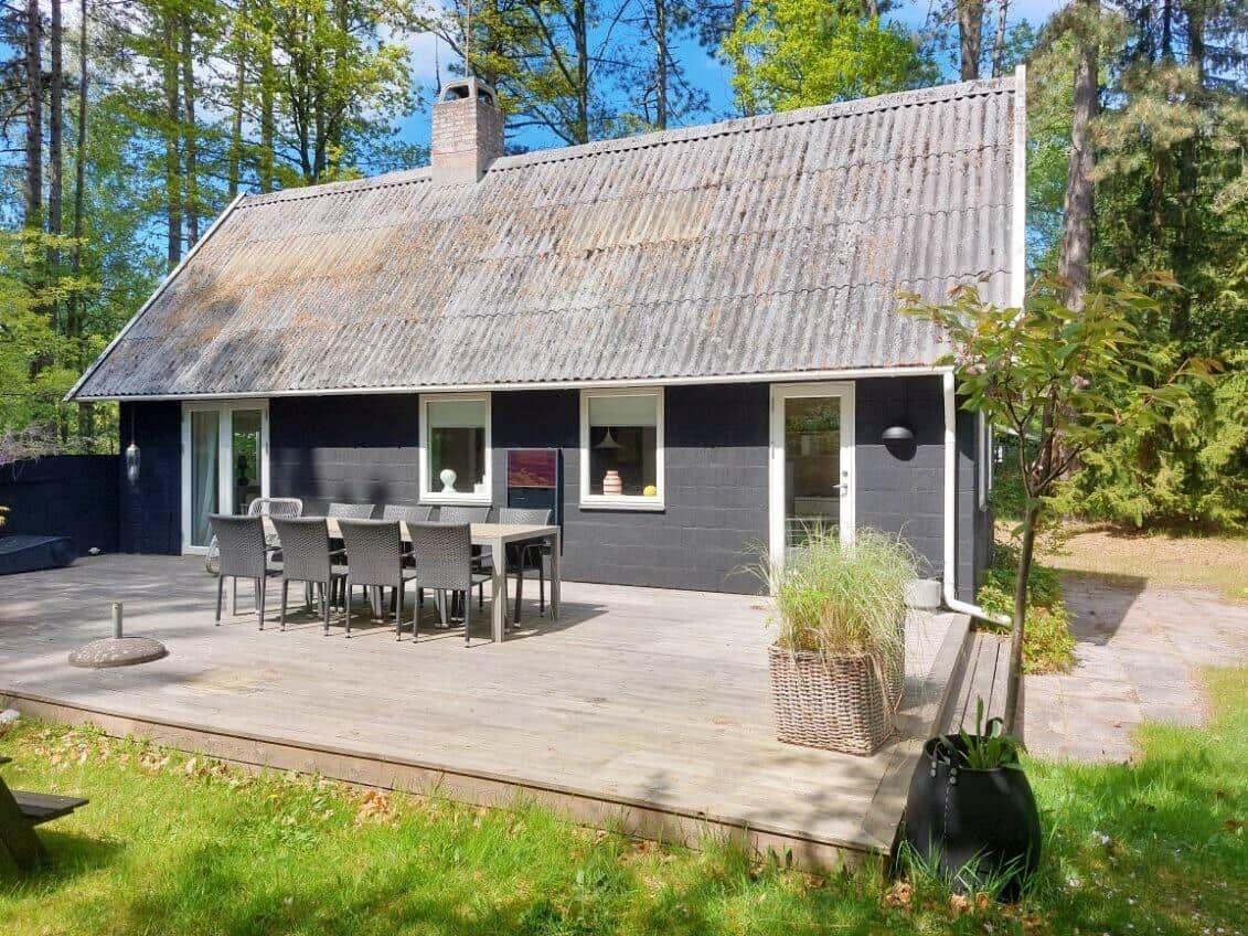 Küche mit weißen Schränken, Herd, Kühlschrank und Fensterblick auf Wald.