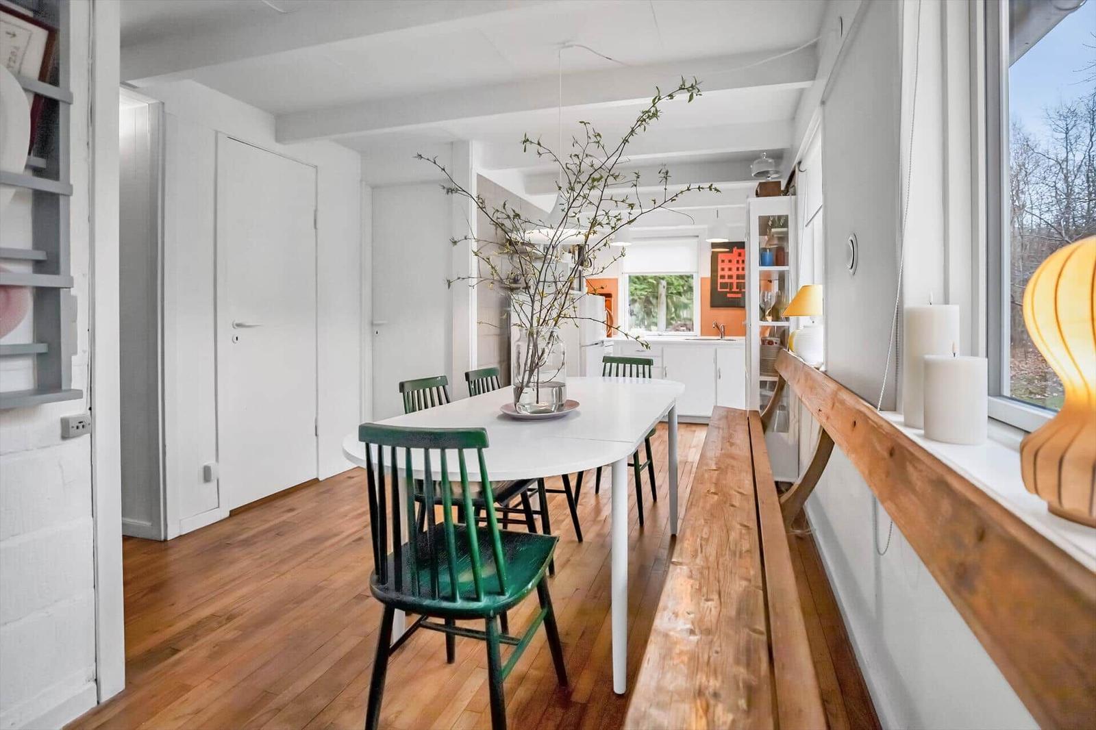 Haus mit Holzboden, Treppe und buntem Glasfenster. Jacke und Hüte hängen an der Wand.