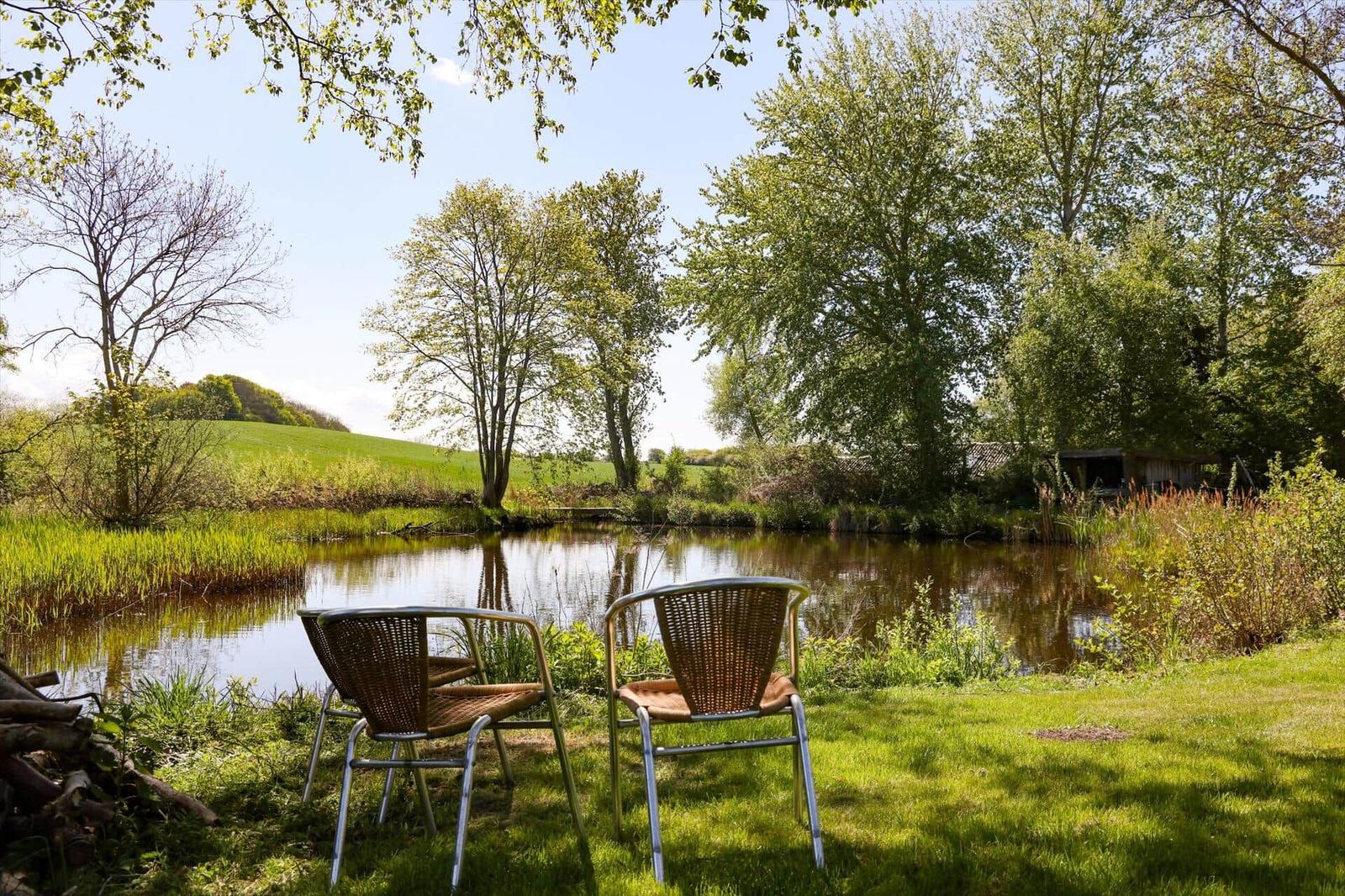 Schwarzes Holzhaus mit Terrasse, Grill und Blüten im Vordergrund.