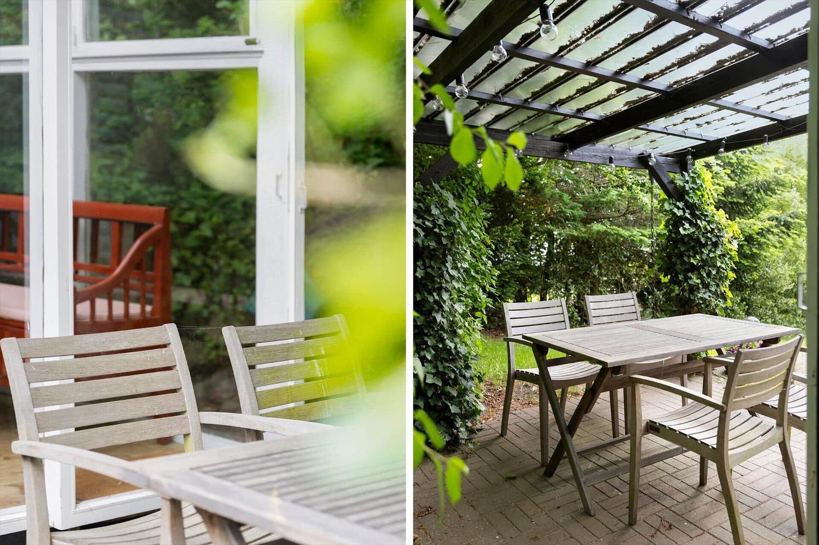 Schwarze Holzhütte mit Terrasse, Sitzbank und grünen Laterne auf Tisch.