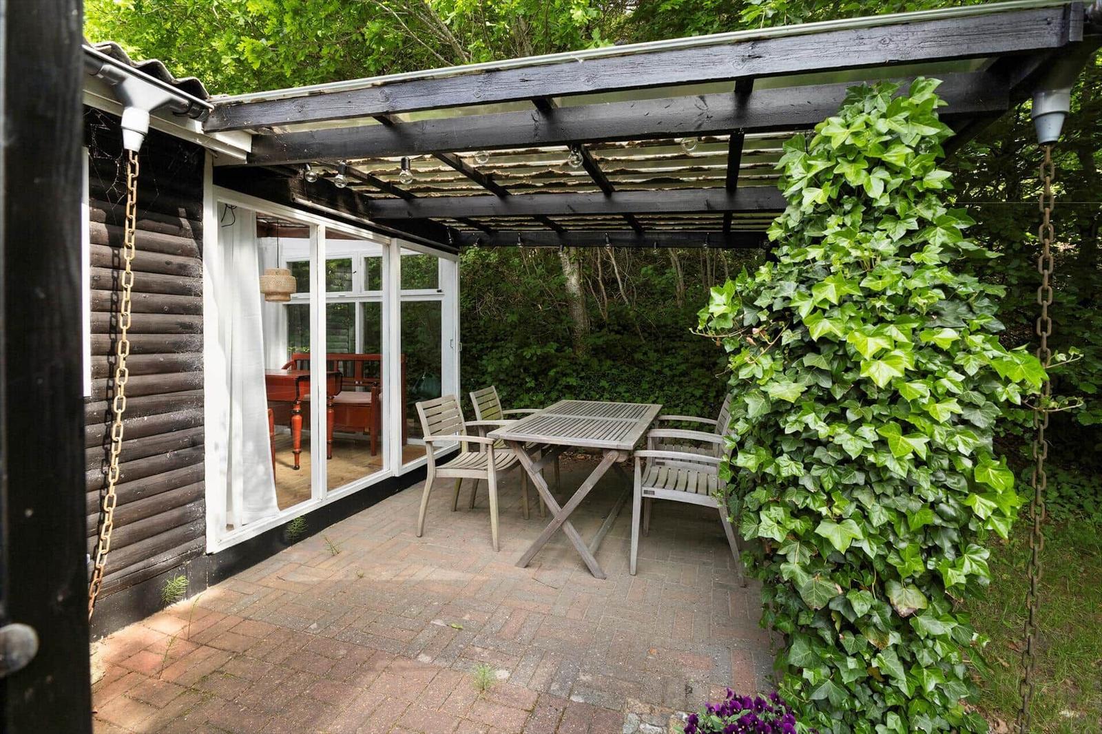 Terrasse mit Holzdielen, Sitzgelegenheiten und Blick in grüne Vegetation.