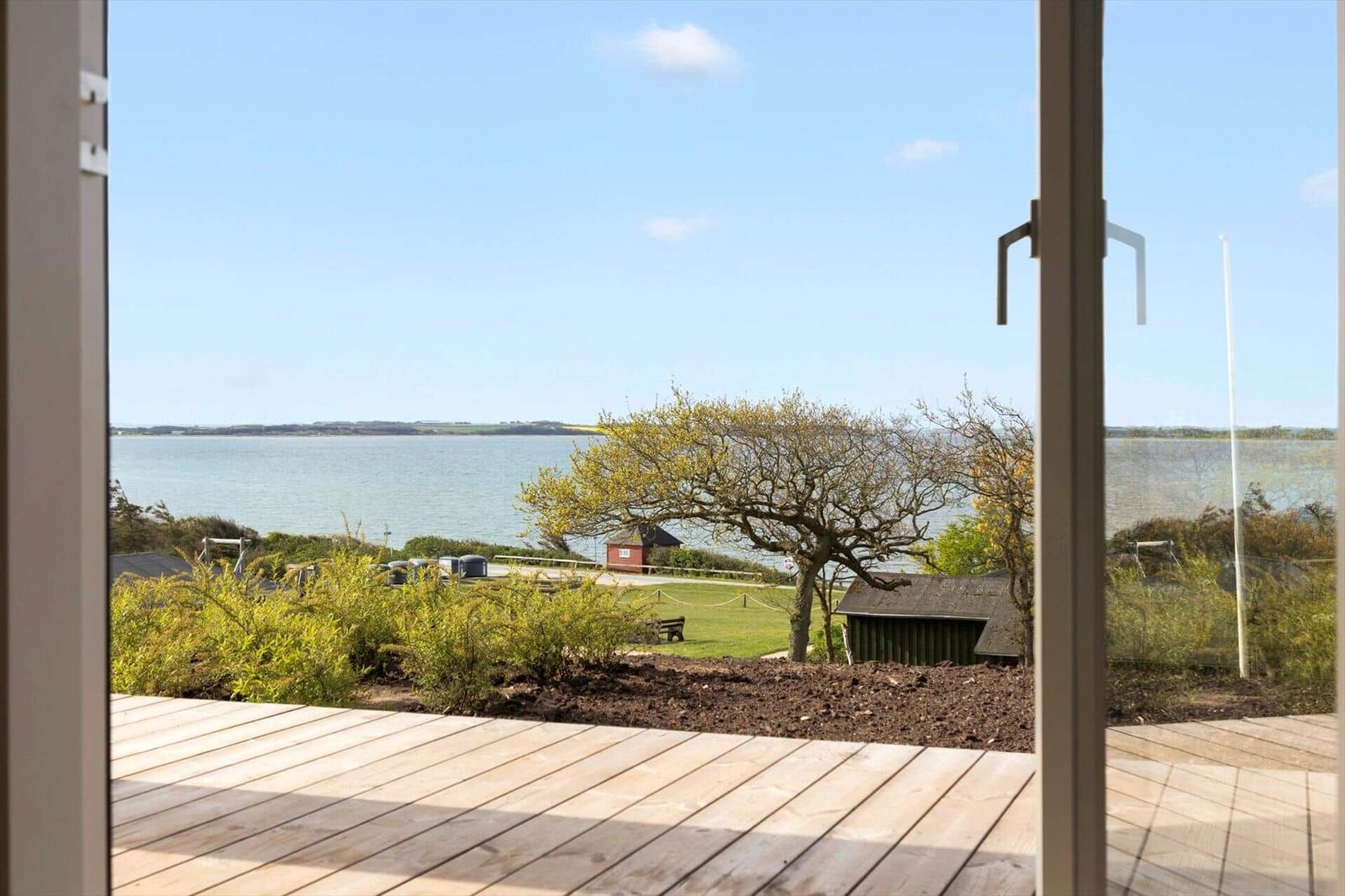 Moderne schwarze Hütte mit Terrasse und Blick auf Wasser