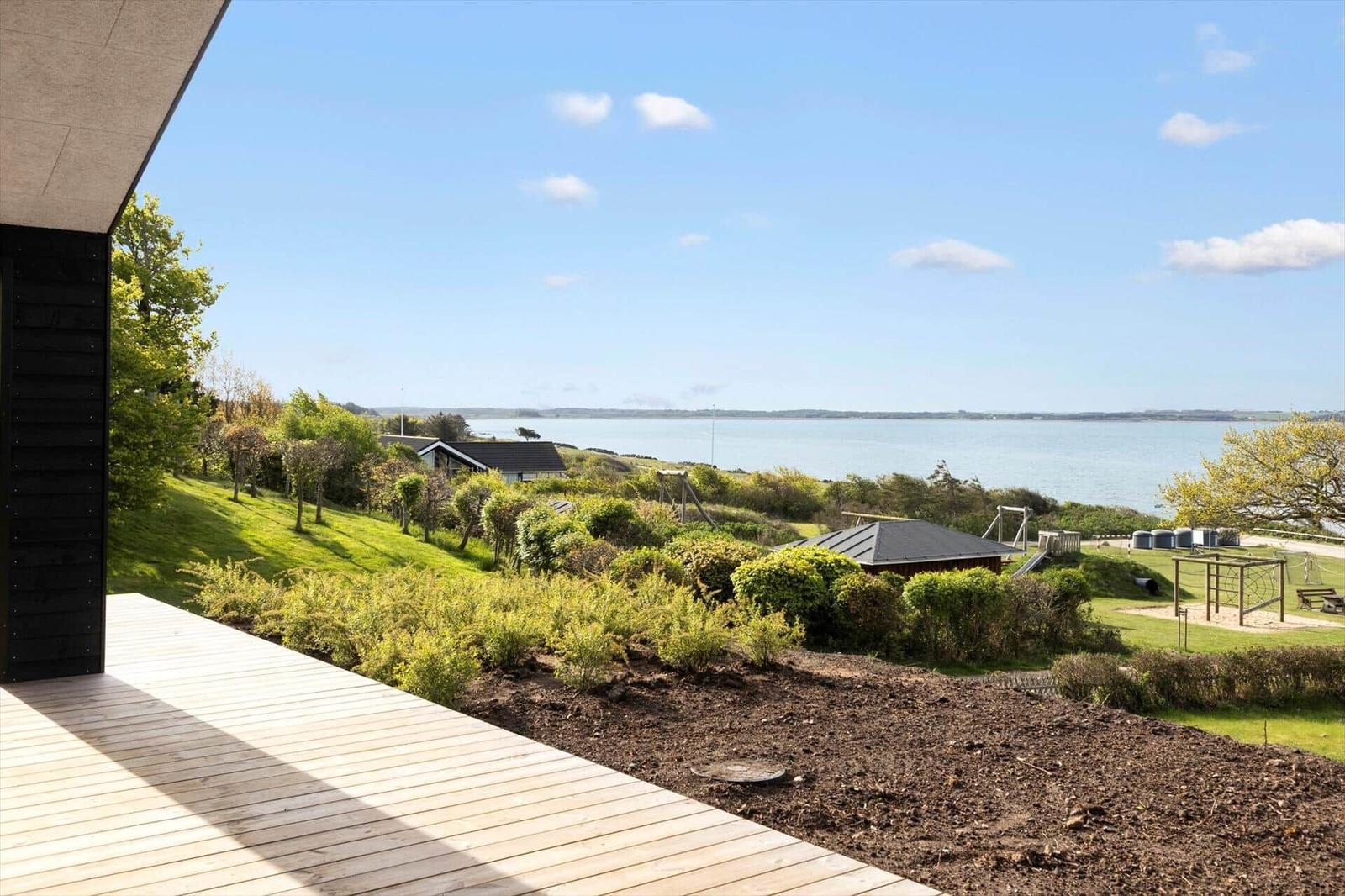 Moderne schwarze Strandhütte mit Terrasse und Blick aufs Meer.