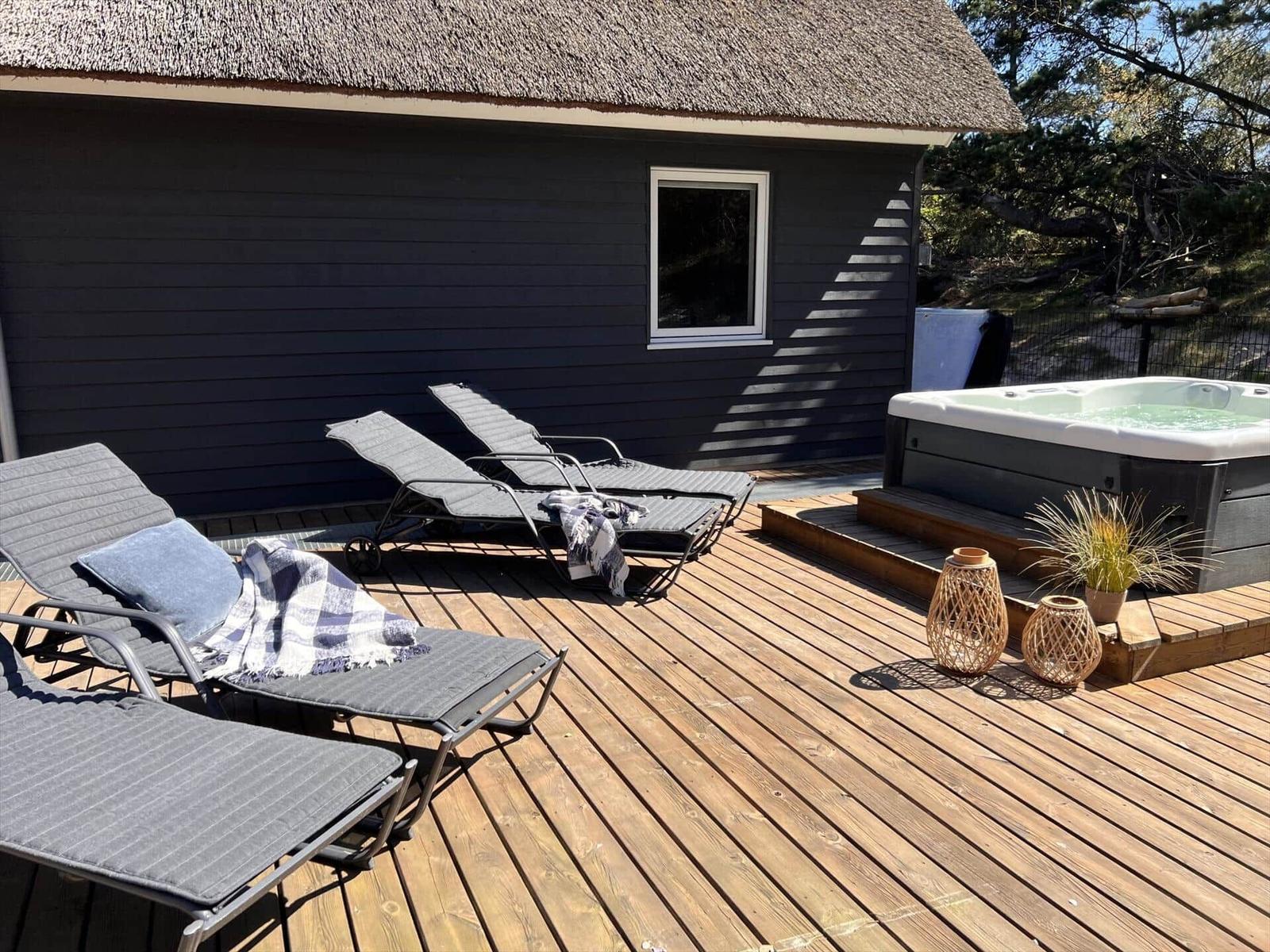 Terrasse mit Whirlpool, Sonnenliegen und Pflanzen.