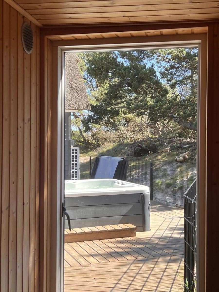 Eine Whirlpool-Badewanne mit Wasserstrahlern auf einer Holterrasse mit Gartenmöbeln.