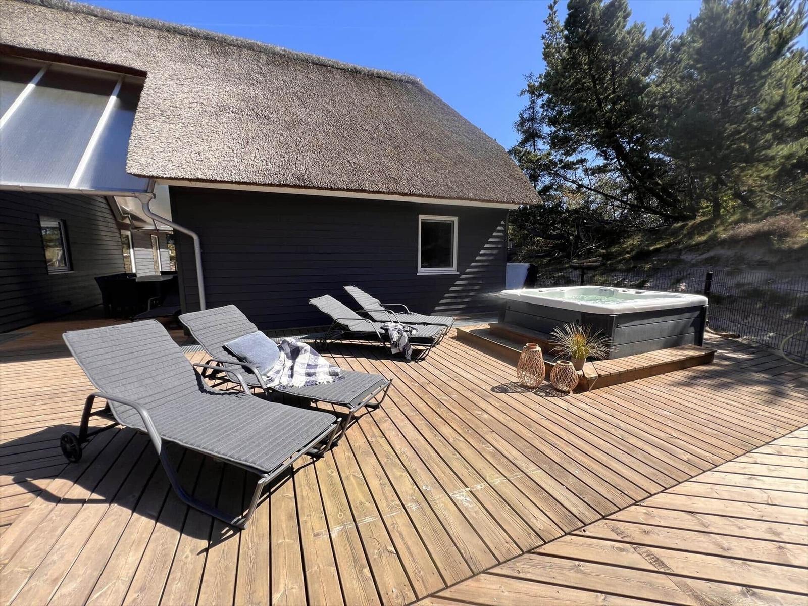 Durch ein rautenförmiges Fenster ist eine Terrasse mit Whirlpool und Bäumen zu sehen.